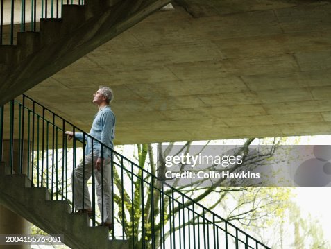 Mature man ascending stairs outdoors, side view Mature man ascending stairs outdoors, side view