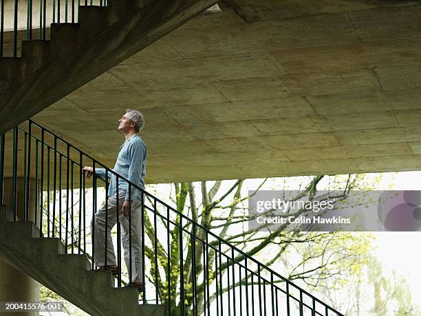 mature man ascending stairs outdoors, side view - subir o bajar escalones fotografías e imágenes de stock