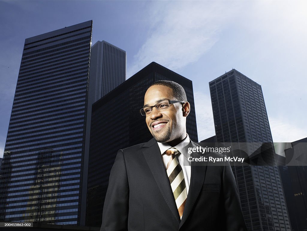 Businessman outdoors, buildings in background