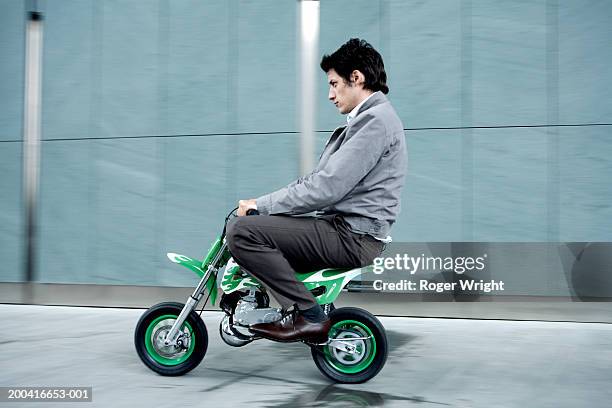 young man riding miniture motorbike, side view (blurred motion) - motorcycle man stock pictures, royalty-free photos & images