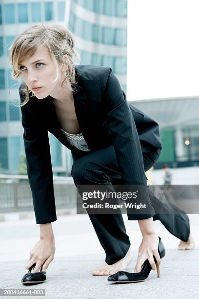 young woman in starting position on pavement, hands in shoes - starting block photos et images de collection