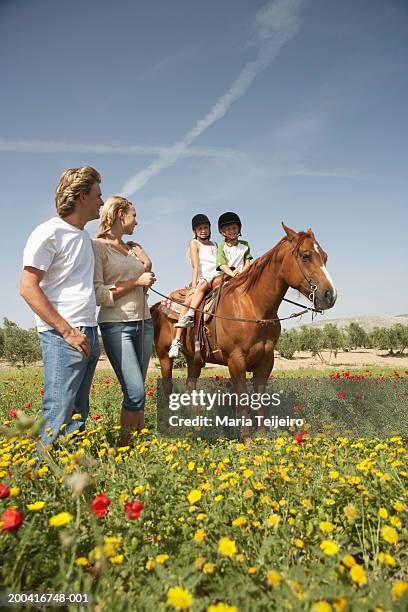 parents leading son and daughter (9-11) on horse, low angle view - enable horse stock-fotos und bilder