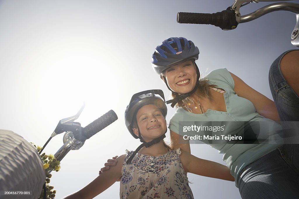 Mother and daughter (9-11) by bicycles, portrait, low angle view