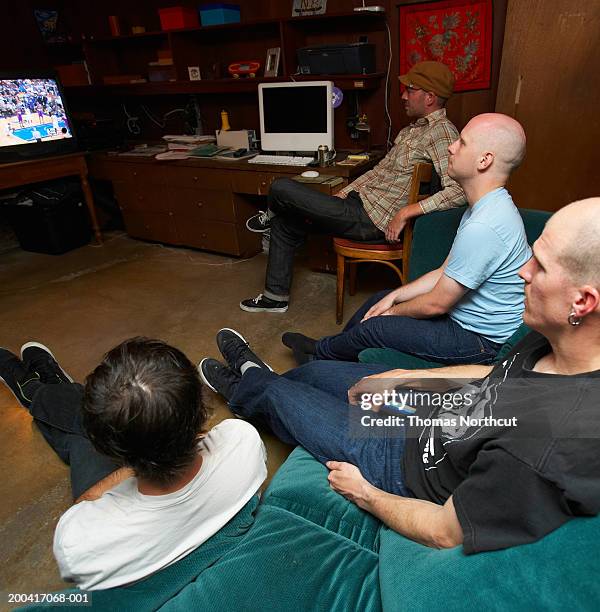 four young men watching television - sports man cave stock pictures, royalty-free photos & images
