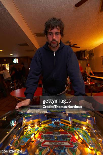 young man playing pinball in bar - pinball stock pictures, royalty-free photos & images