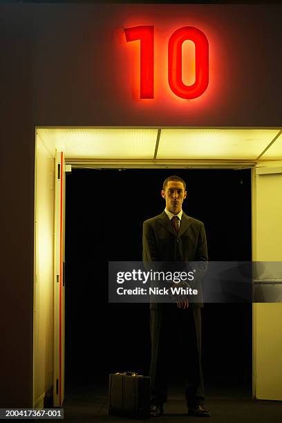 businessman by door under neon '10' sign, portrait - ten of clubs bildbanksfoton och bilder