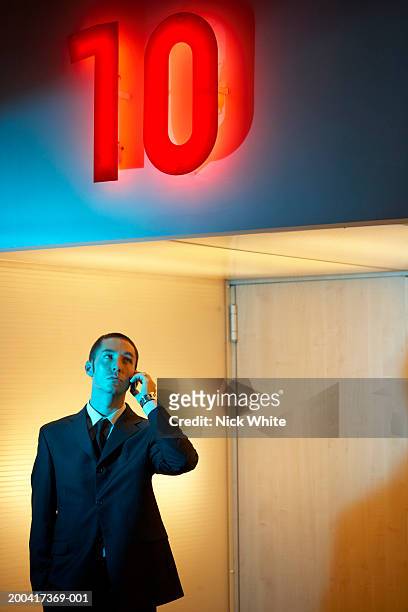 businessman using mobile phone under neon '10' sign - ten of clubs bildbanksfoton och bilder
