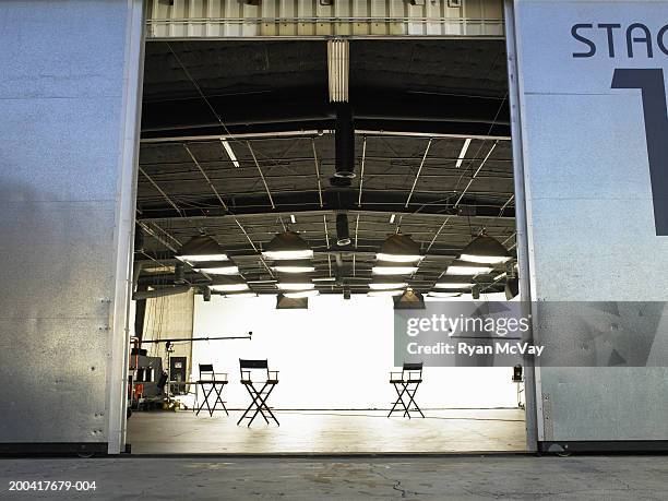 lighting equipment and folding chairs in film studio - filmindustrie stock-fotos und bilder