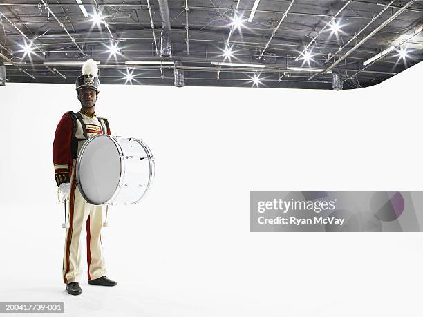 man in marching band uniform carrying bass drum, portrait - bass drum stock-fotos und bilder