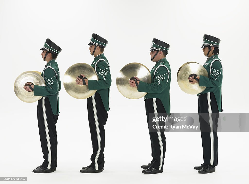 Four teenagers (14-18) in band uniforms holding cymbals, side view