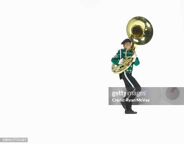 teenage boy (16-18) in marching band uniform playing tuba, side view - tube foto e immagini stock