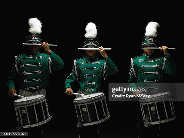 three teenage boys (14-17) in marching band uniforms playing drums - banda de marcha fotografías e imágenes de stock