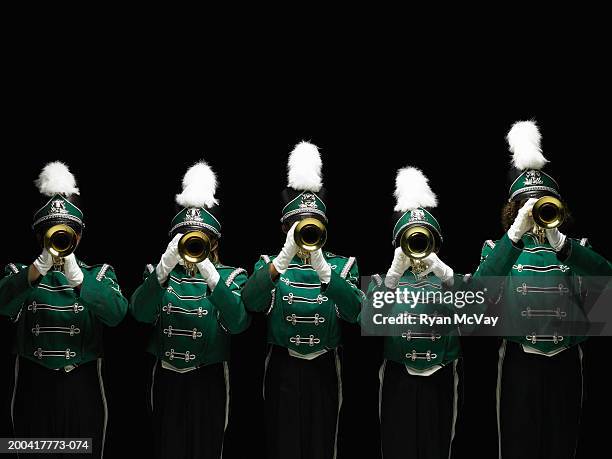 five teenagers (14-18) in marching band uniforms playing trumpets - uniformité photos et images de collection