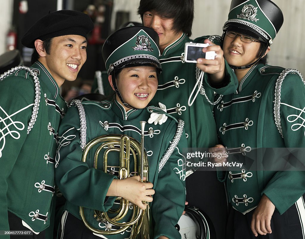 Teenagers (14-17) in marching band uniforms photographing themselves