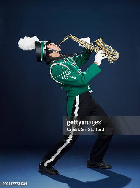 teenage boy (16-18) in band uniform playing saxophone, side view - marching band stock pictures, royalty-free photos & images