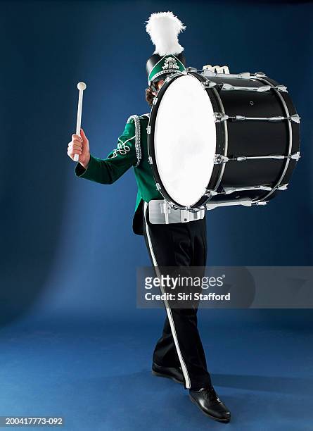 teenage boy (13-15) in marching band uniform playing bass drum - bass drum stock-fotos und bilder