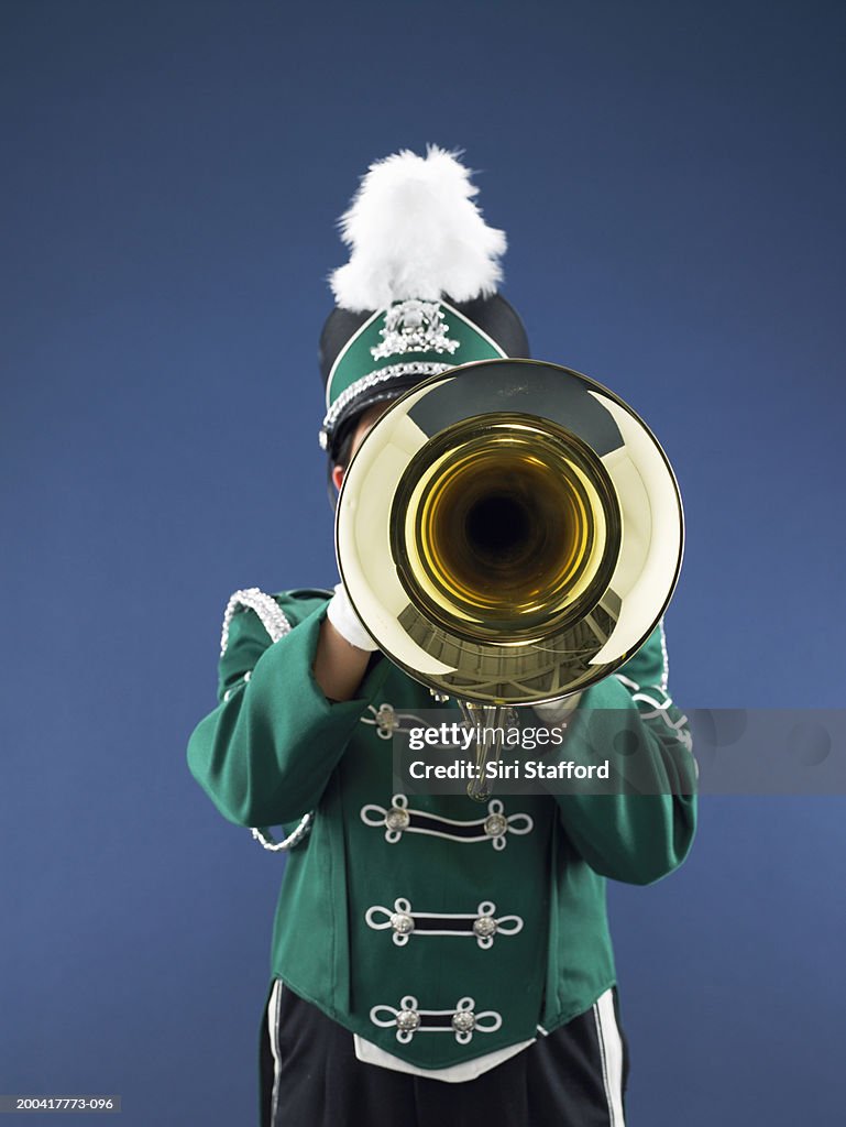 Teenage girl (14-16) in marching band uniform playing horn