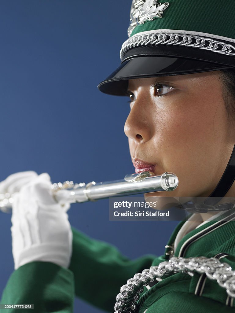 Teenage girl (15-17) in marching band uniform playing flute