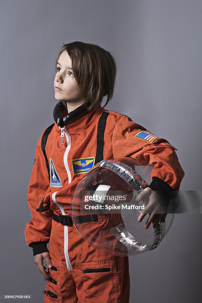 Girl (7-9) wearing astronaut costume, looking up