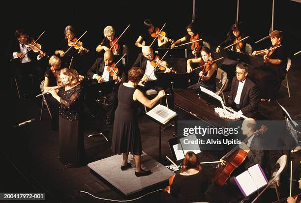 mature woman performing flute solo with orchestra, overhead view - conductor leading orchestra stock-fotos und bilder