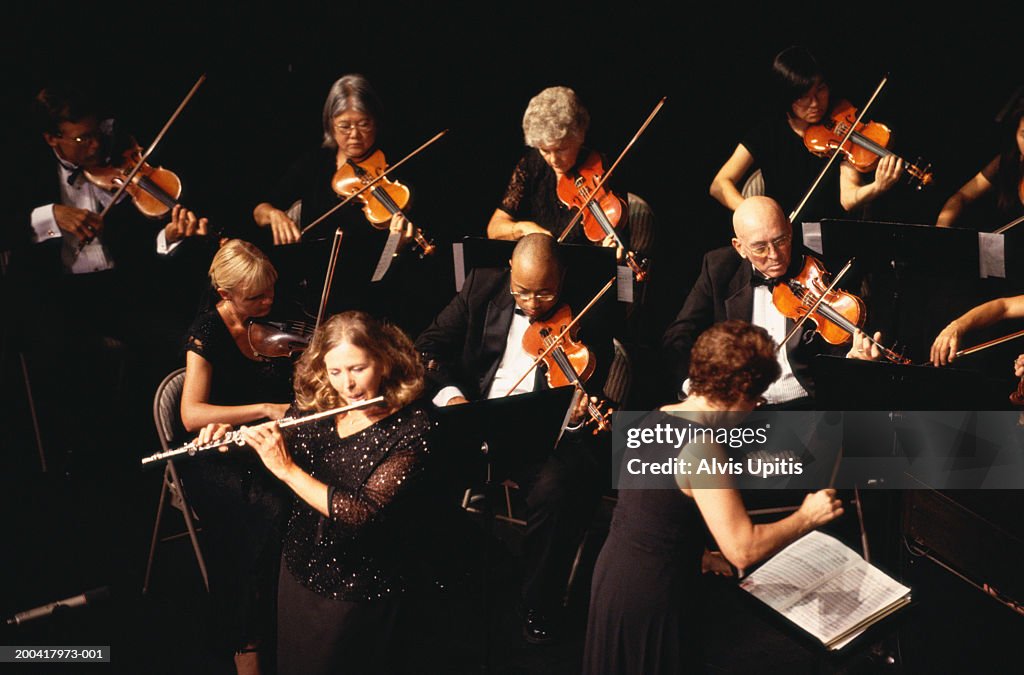 Mature woman performing flute solo with orchestra, overhead view