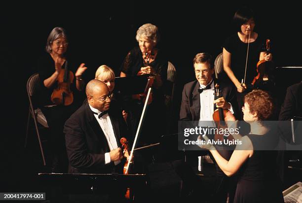 female conductor applauding violin section in orchestra - dirigent stock-fotos und bilder