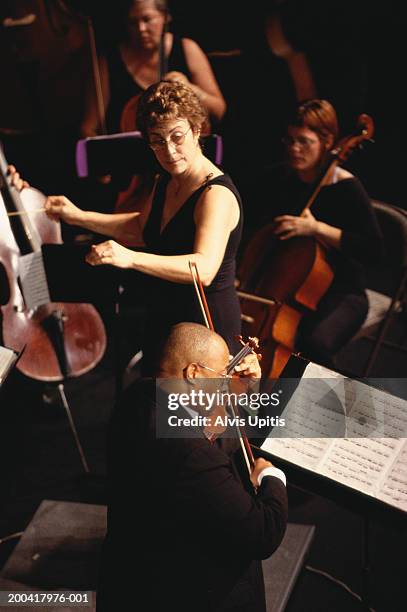 female conductor and male violin soloist performing in orchestra - conductor leading orchestra stock-fotos und bilder