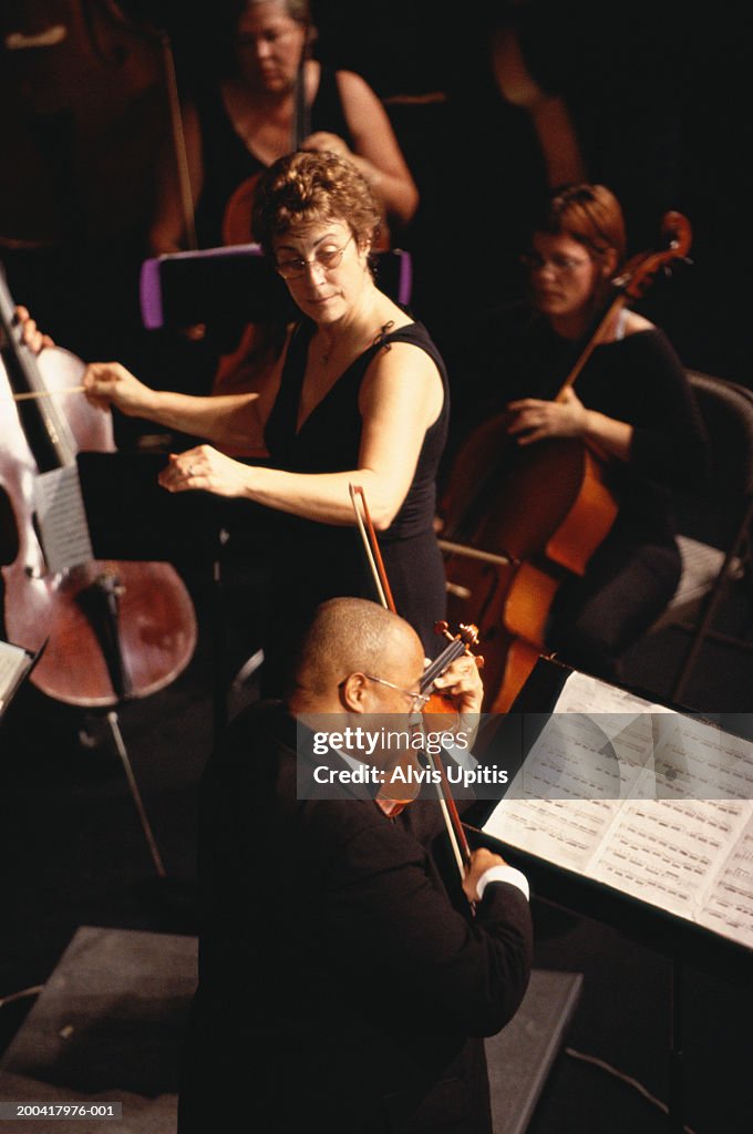 Female conductor and male violin soloist performing in orchestra