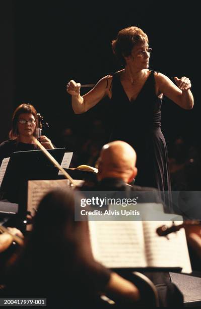 female conductor performing with orchestra (focus on woman) - conductor leading orchestra stock-fotos und bilder