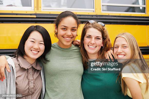 four teenage girls (15-17) standing beside school bus, portrait - female high school student stock pictures, royalty-free photos & images