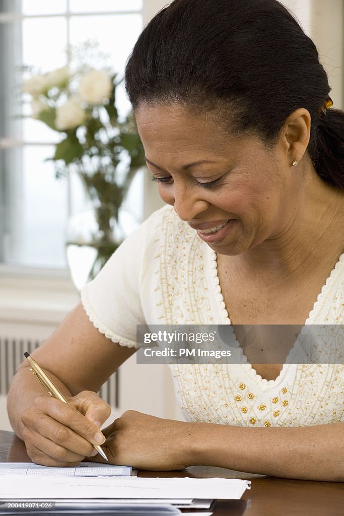 Mature woman writing check in home office