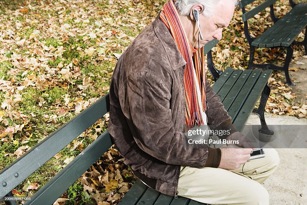 Senior man on bench using cell phone, elevated view