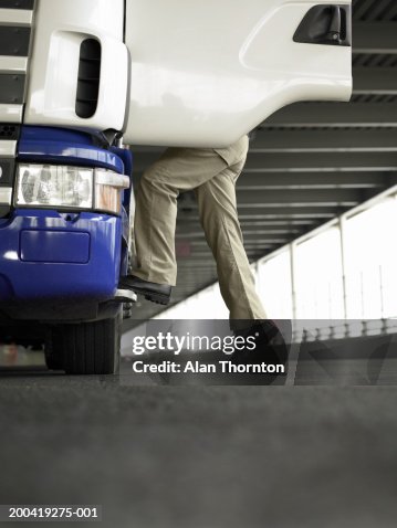 Man climbing into truck, ground view Man climbing into truck, ground view