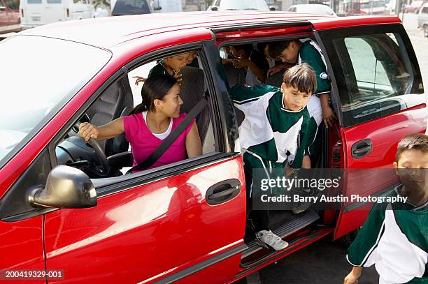 woman in car looking at boys (7-11) football team in back - soccer mum stock-fotos und bilder