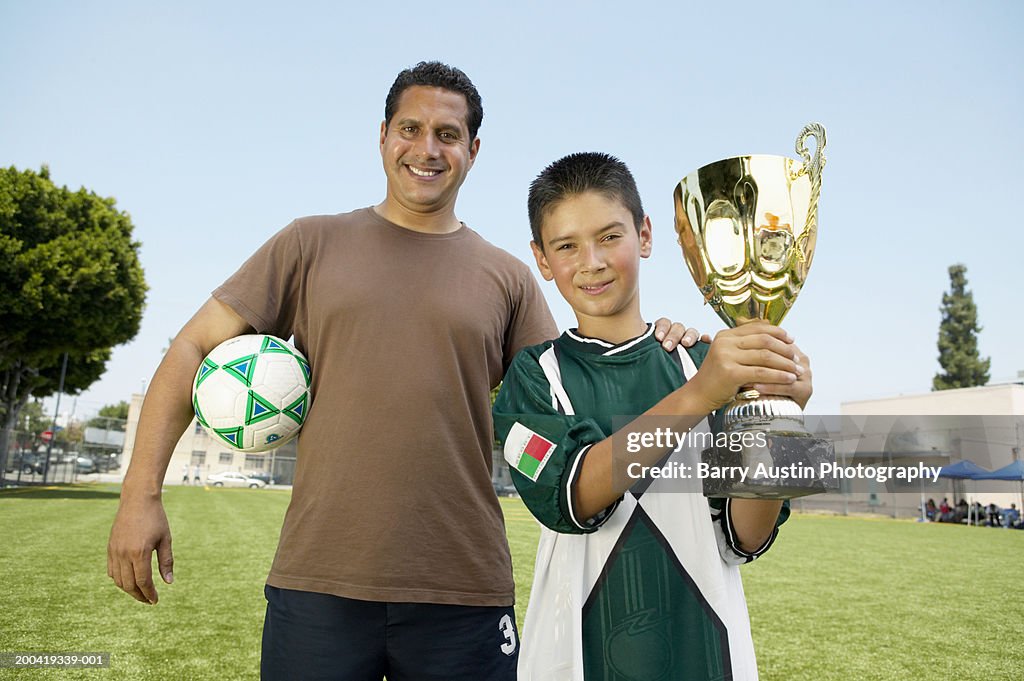 Vaters hand auf dem son's (7 und 9) Schulter, junge holding trophy, portr