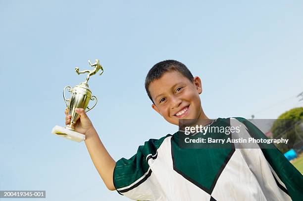 boy (7-9) holding up trophy, smiling, portrait, low angle view - title nine imagens e fotografias de stock