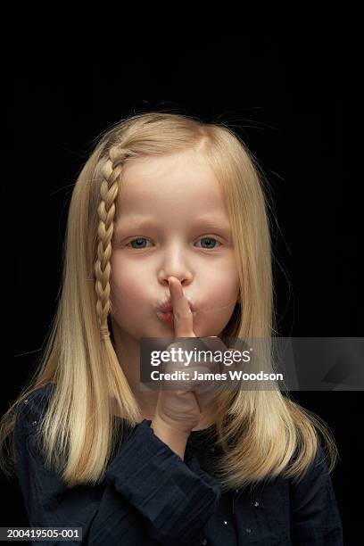 girl (5-7) with finger on lips, portrait, close-up - blonde hair black background stock pictures, royalty-free photos & images