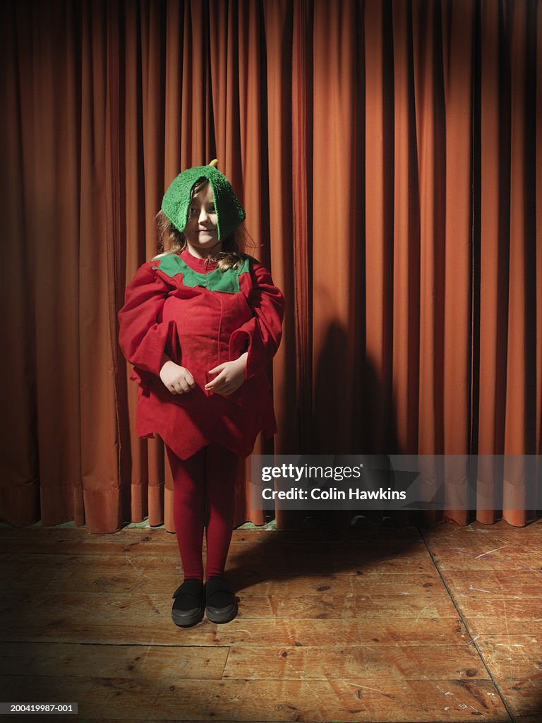 Girl (4-6) standing on stage wearing tomato costume, portrait