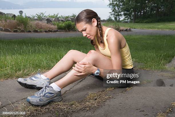 woman jogger holding injured knee - wounded photos et images de collection