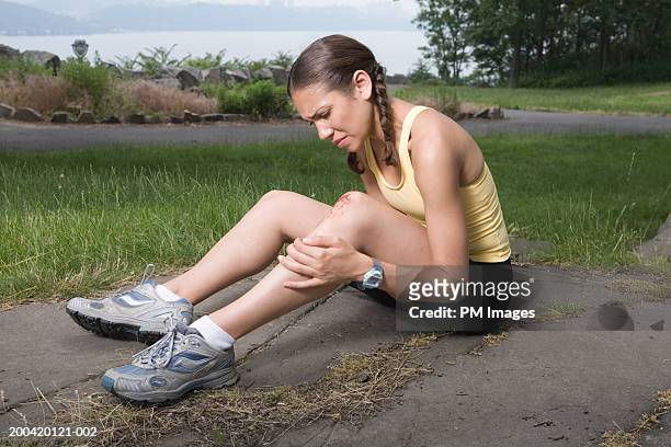 woman jogger holding injured knee - wounded stockfoto's en -beelden