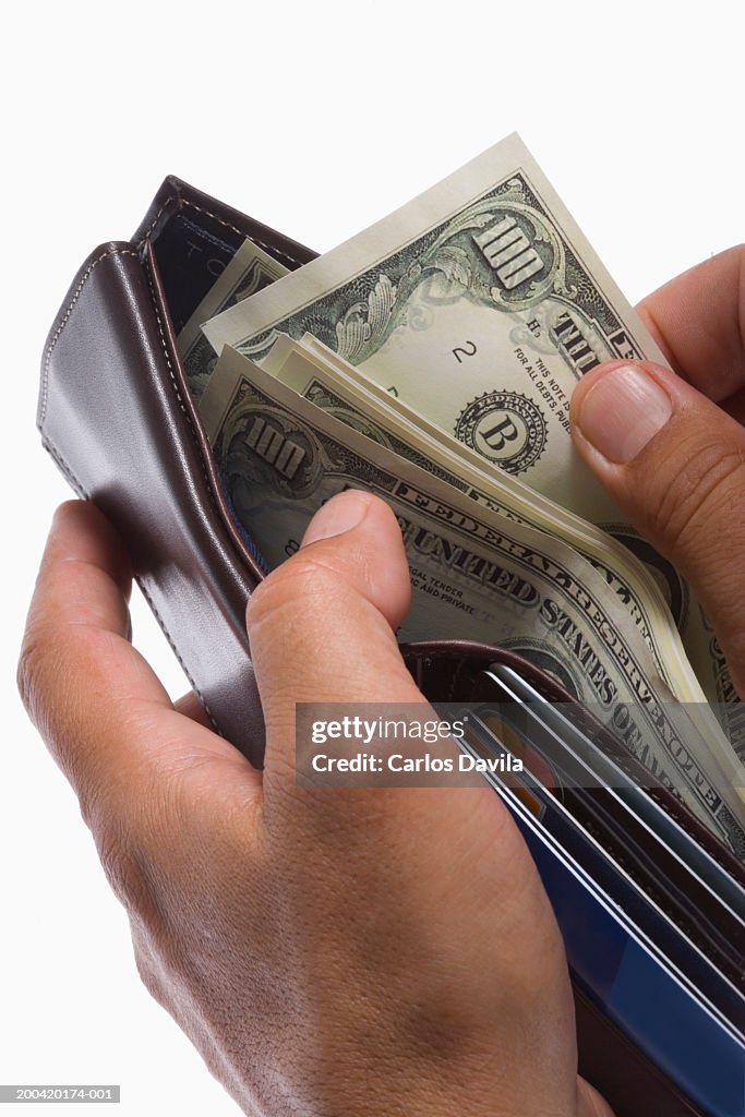 Man holding wallet with US $100 bills, close-up