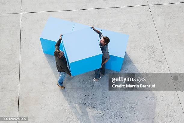 two men carrying large blue block, elevated view - wood block stacking stock pictures, royalty-free photos & images