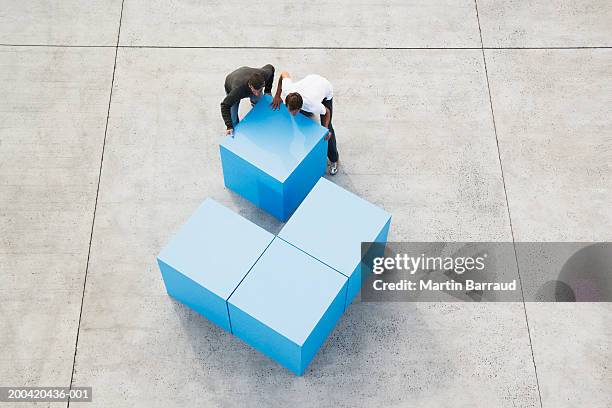 two men moving large blue block, elevated view - soluzione foto e immagini stock