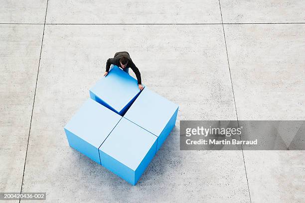man moving large blue blocks, elevated view - conclusion photos et images de collection