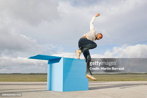 man jumping out of large blue box - appearance imagens e fotografias de stock