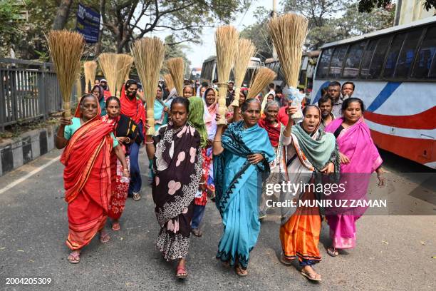 Women supporters of the ruling Bangladesh Awami League party carry brooms during a protest against Nobel peace laureate Muhammad Yunus, along a...