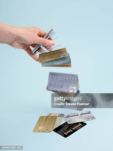 woman dropping stack of credit cards (focus on hand) - credit card and stapel stockfoto's en -beelden