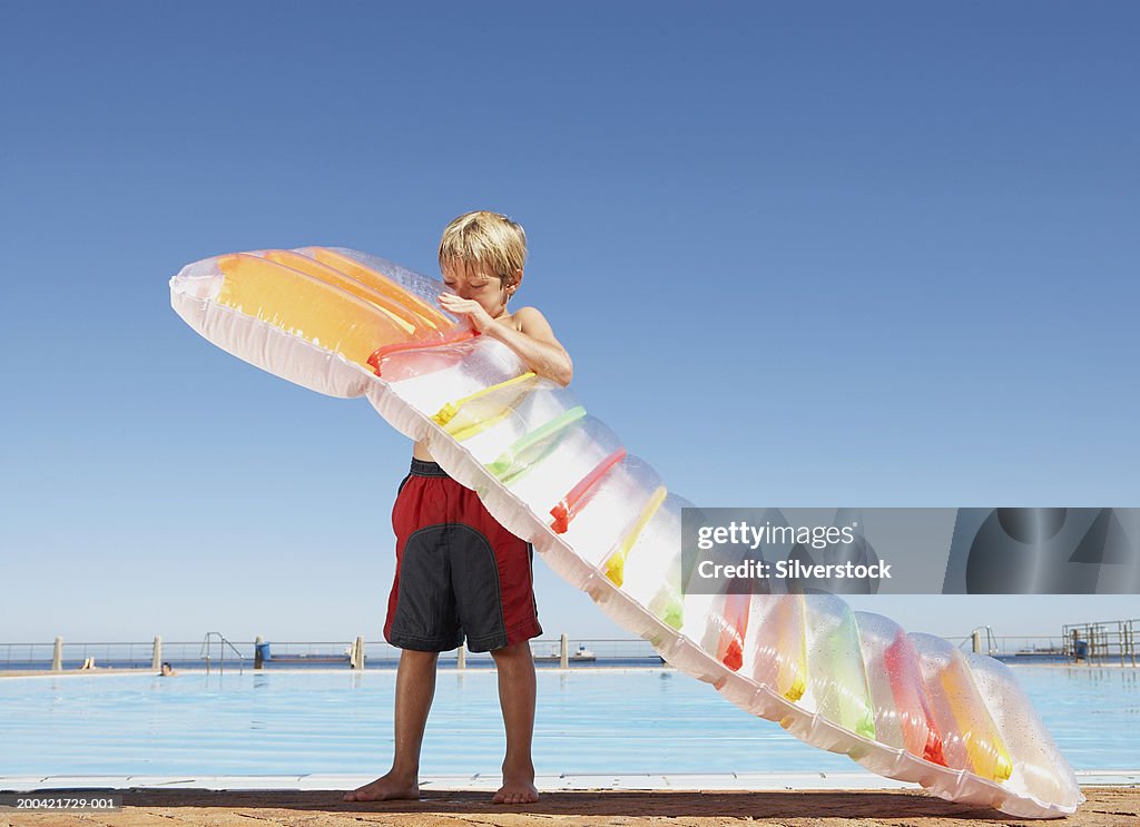 Boy Inflatable Raft Boy Blowing Up Inflatable Raft By Outdoor Swimming Pool High-Res Stock ...