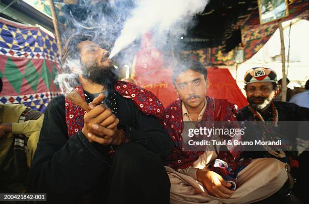 pakistan, sind, man smoking chillum by friends, portrait - smoking chillum fotografías e imágenes de stock