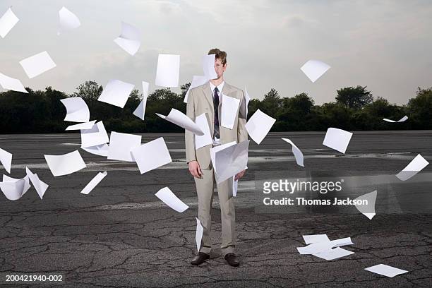 businessman caught in storm of swirling papers (composite) - bureaucracy stock pictures, royalty-free photos & images